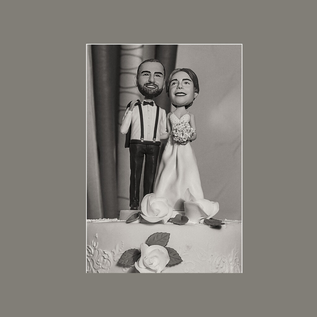 Schwarz-Weiß Hochzeitsfoto. Die Hochzeitstorte zeigt das Brautpaar als Marzipanfiguren.