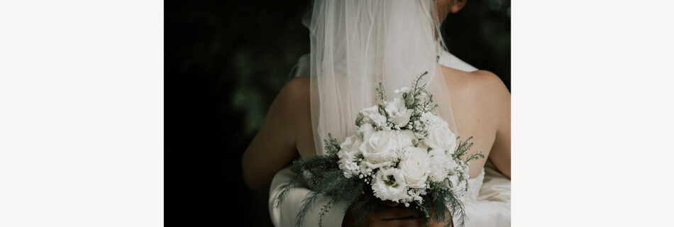 Braut von hinten mit Brautstrauß cor dem Rücken